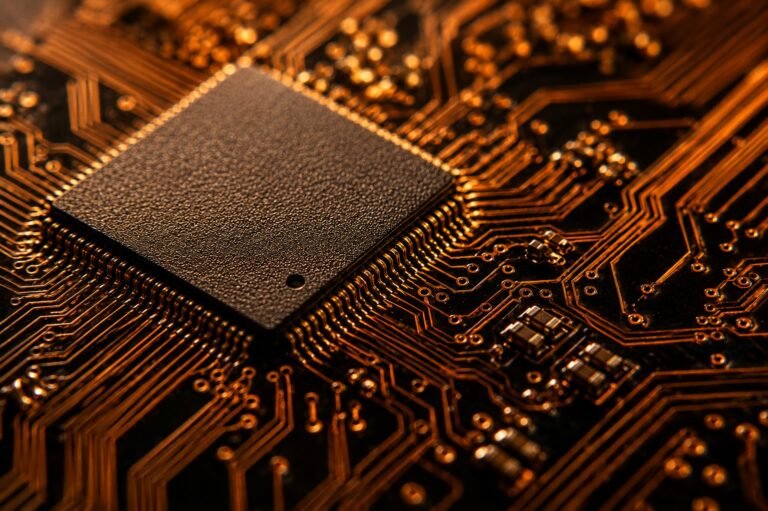 Close-up of a circuit board with a chip package and warm copper circuit traces against a dark background