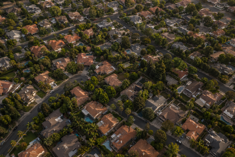 Aerial view of a suburban residential neighborhood with rows of houses and tree-lined streets